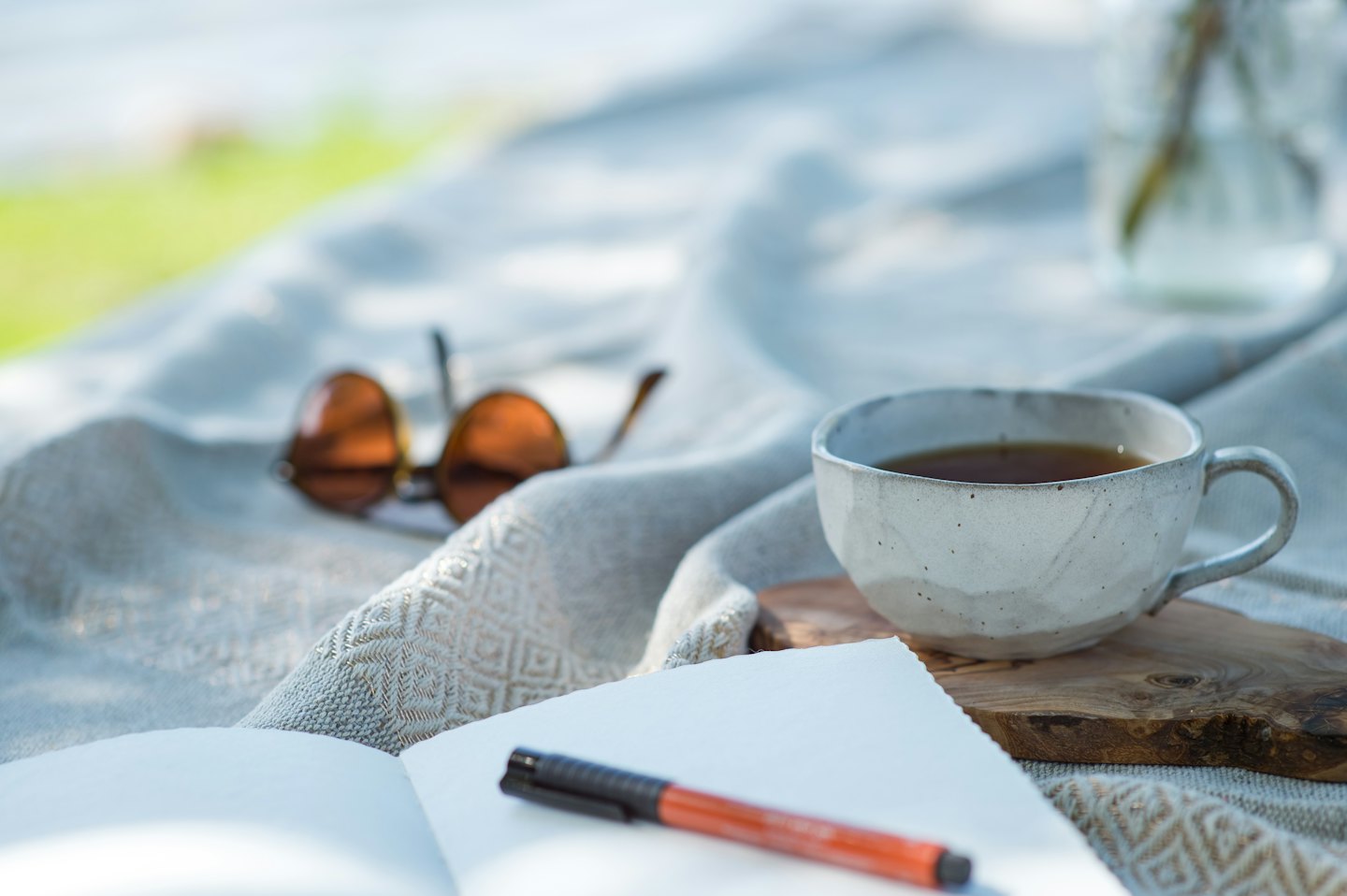 Tea cup and notebook resting on a cozy outdoor blanket.