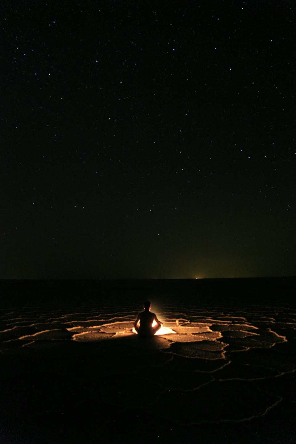 Person meditating under a starry night sky.